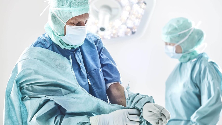 Chirurgas užsivelka operacinį chalatą