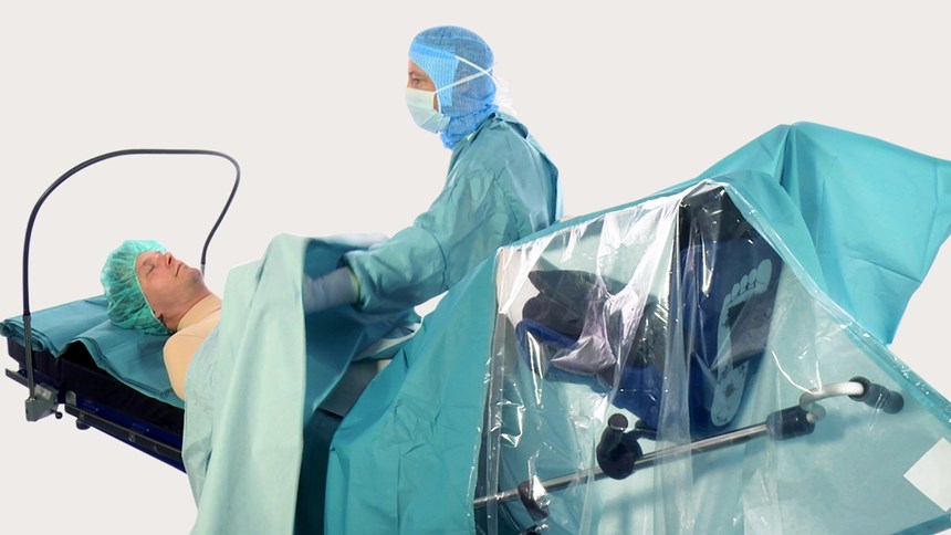 Sveikatos priežiūros specialistas, naudojantis „BARRIER“ apklotą chirurginei procedūrai.